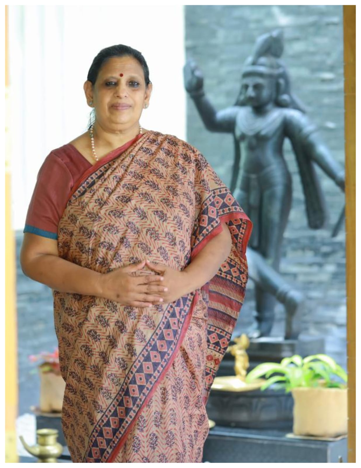 Krishnamani Ma'am beside a bronze Krishna murti — a portrait of devotion